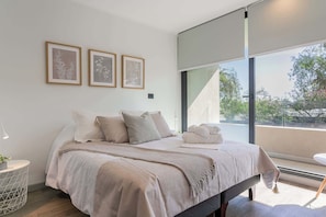 Experience tranquility in this beautifully designed bedroom, featuring soft linens and abundant natural light for a restful stay.