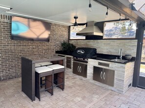 Outdoor kitchen with seating for four and TV