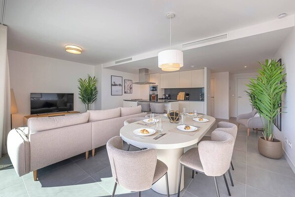 Spacious and inviting living room with a large sofa, TV, and dining area. Direct terrace access. (1)
