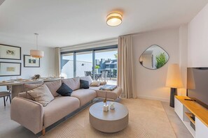 Spacious and inviting living room with a large sofa, TV, and dining area. Direct terrace access. (2)