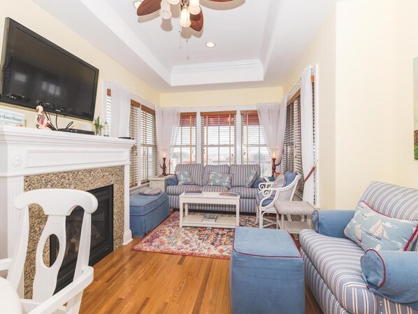 Spacious living area with natural light and a mounted TV for entertainment.