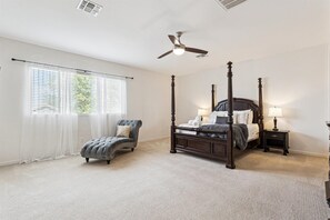 Primary Bedroom featuring a Queen bed, Smart TV, chaise lounge chair, walk-in closet, and an en-suite bathroom