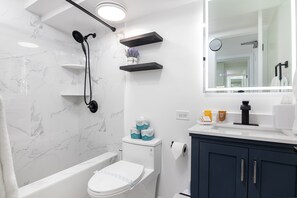 Modern and stylish bathroom featuring sleek black fixtures, marble-tiled shower, and elegant vanity with ample lighting.