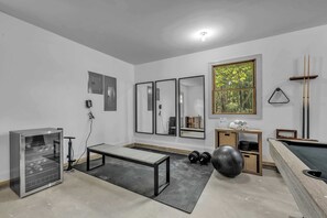 Multi-Purpose Fitness & Game Room – A versatile space equipped with workout essentials, a sleek bench, full-length mirrors, and a pool table for the perfect mix of fitness and fun.