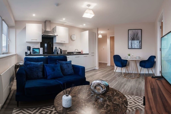 Relax in the stylish and cosy living room, featuring a plush sofa, smart TV, and plenty of natural light for a welcoming atmosphere.