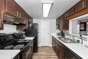 Functional kitchen with oven, stove, fridge and basic cooking ware