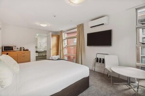 Studio apartment featuring a kettle, microwave, toaster, bar fridge, widescreen smart tv, heat pump (aircon) and small table and two chairs.