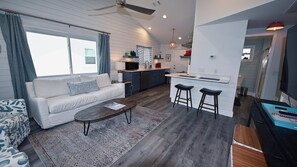Relax in the spacious living room, featuring a plush sofa, and smart TV. The large windows offer plenty of natural light and stunning views of nature.