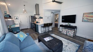 Relax in the spacious living room, featuring a plush sofa, and smart TV. The large windows offer plenty of natural light and stunning views of nature.