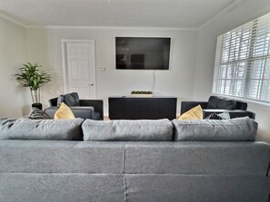 Plenty of natural light. The living area features a 65-inch Samsung Smart TV with access to Netflix and other apps (cable and streaming services not provided). Relax on the sofa and chairs with convenient drink side tables.
