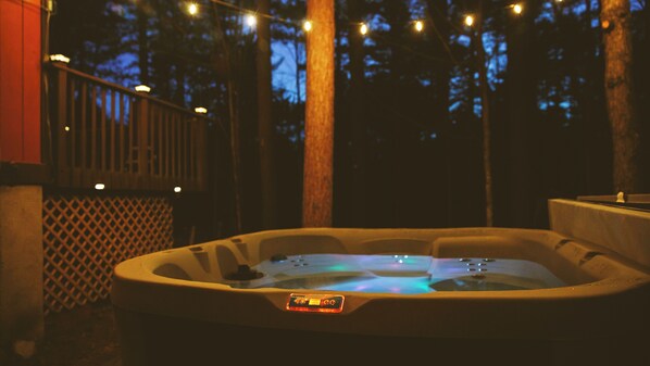 Soak under the stars, surrounded by forest stillness and a warm, glowing light 