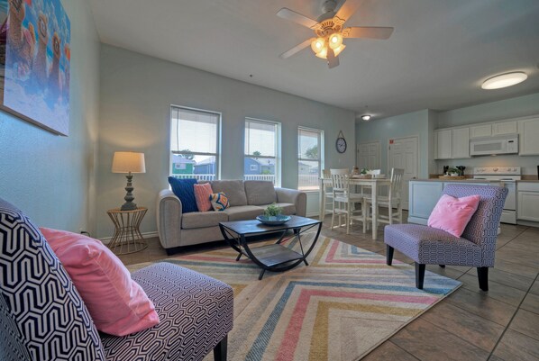 The living room has coastal-inspired décor, plush seating, and a sleeper sofa.