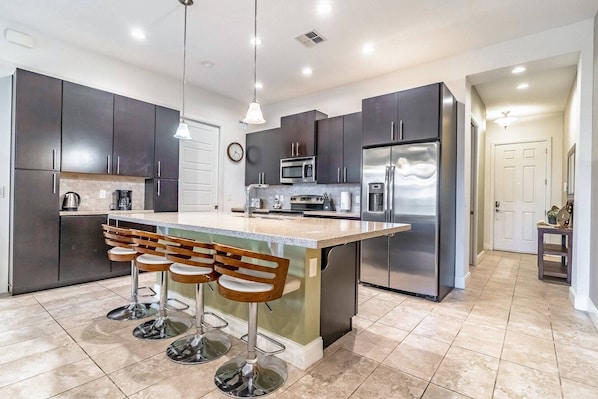 Fully stocked kitchen with stainless steel appliances and island seating for 4