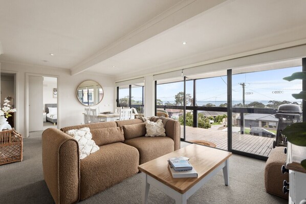 Main lounge overlooking front bay facing deck, aircon, heating, comfy lounge and smart tv