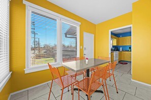 Dining Room: Enjoy meals in this sunlit dining area with bold yellow walls, large windows overlooking the backyard, and trendy orange chairs.