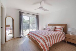 Step straight onto the deck from the primary suite, featuring a queen bed and a ceiling fan for comfort.
