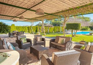 Terrasse couverte avec canapés et tables de jardin au bord de la piscine