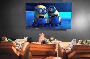 Family movie night cozy living room with large TV, comfy sofas, and popcorn