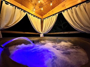 Worries and cares? Not here,  melt them away in the 5 person, private hot tub, while enjoying the warm glow from the overhead string lights.
