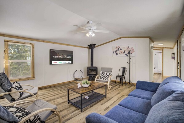 Unwind in the cozy living room featuring plush seating, a large Smart TV for movie nights, and peaceful forest views through the windows. 
Please note the indoor fireplace is not available for guest use at this time. We appreciate your understanding.