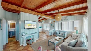 The coastal chic design flows seamlessly through an open concept living area and fully equipped kitchen. The space is designed for socializing and comfort, providing a backdrop for memorable moments with family and friends.