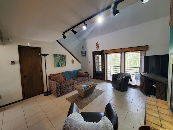 Living room with private balcony facing the tree line and the ski area