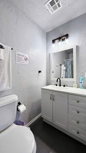 Enjoy a sparkling clean bathroom with a sleek vanity, bright lighting, and plush towels for a spa-like experience.