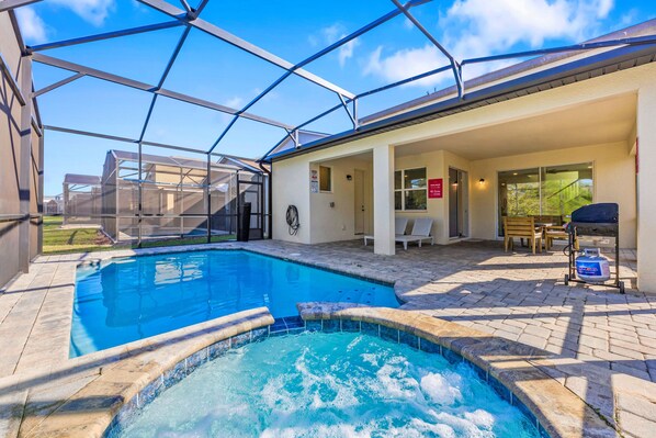 Relax in the private screened in pool and bubbling spa, perfect for any time of day - Covered patio with outdoor seating and a grill makes dining al fresco a breeze - Unwind in this peaceful space, just steps from comfort and fun filled moments