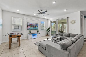 Spacious living area with a cozy sectional, perfect for movie nights & relaxation - Enjoy friendly competition with the foosball table or unwind with your favorite show - Sliding doors open to a screened patio, blending indoor with outdoor serenity
