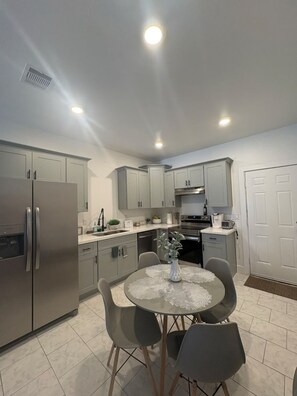 Kitchen with dining table, microwave, stove, refrigerator, toaster, coffee maker