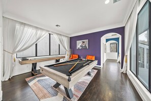 Unwind in the game room, featuring shuffleboard, pool table, & sitting area.