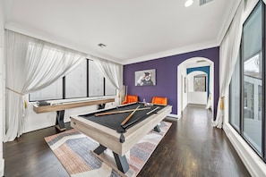 Unwind in the game room, featuring shuffleboard, pool table, & sitting area.