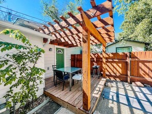 The porch is outfitted with a dining table and charcoal grill