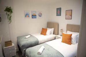 Second bedroom featuring twin beds with fresh white bedding and storage.