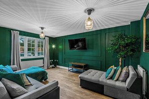 A refined blend of elegance and comfort, this living room features high ceilings, statement lighting, and plush seating bathed in natural light. Premium fabrics, rich wood accents, and exquisite décor create an inviting atmosphere for relaxation.