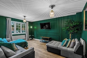A refined blend of elegance and comfort, this living room features high ceilings, statement lighting, and plush seating bathed in natural light. Premium fabrics, rich wood accents, and exquisite décor create an inviting atmosphere for relaxation.