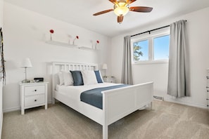 Primary bedroom with a queen bed, closet, dresser, blackout blinds & a Smart TV.