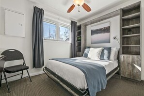 Second bedroom with a double bed, closet, dresser, blackout blinds & a dedicated workstation..