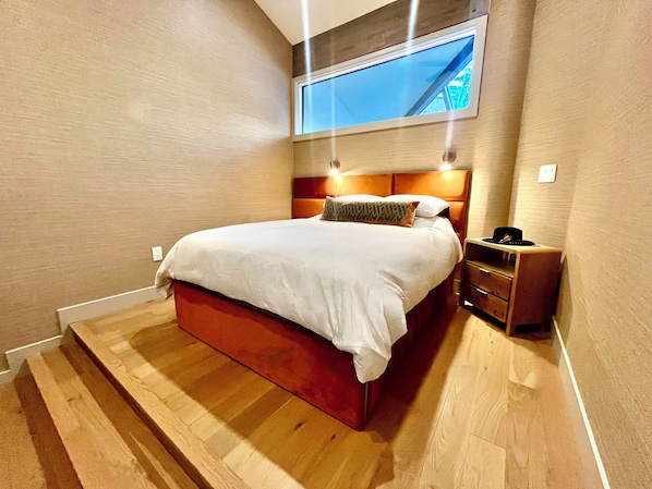 Primary bedroom suite with heated floors under stair lighting and mountain views