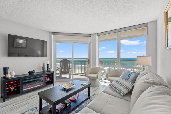 Enjoy gorgeous sunrises and cherish memorable experiences in this 2br 2ba oceanfront resort condo with all the amenities.  This living room is equipped with a Smart TV, Fireplace,  leather couch, and swivel oceanfront chairs.  Balcony access as well.