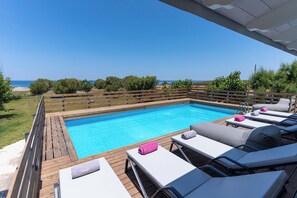 Pool area with luxurious sunbeds and sea views.