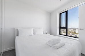 Recharge in the first bedroom's queen bed and wake up refreshed with city skyline views and a built-in mirrored wardrobe for effortless organisation.
