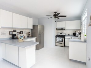 Fully equipped kitchen with pots, dishes, wine glasses, and more.
