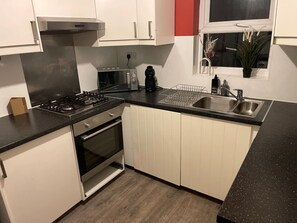 A modern kitchen featuring well-organized shelves, essential appliances, and a spacious washing area.