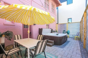 Fun back patio with hot tub, table, and chairs.
