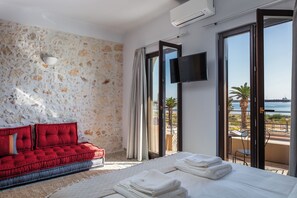 It is a spacious room with a double bed, a sofa and a medium-sized television.  