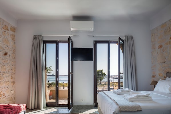 It is a spacious room with a double bed, a sofa and a medium-sized television.  