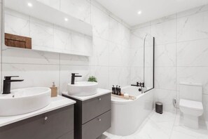Main bathroom with double sink, bathtub, and built-in bidet for comfort and ease