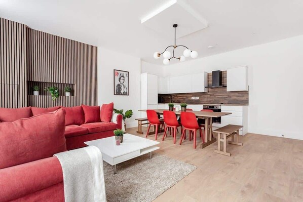 Luxe living room with wood panels, open kitchen, 75" TV, and air conditioning.