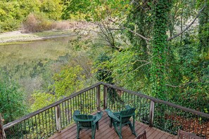 The back deck overlooks the river through lush foliage.